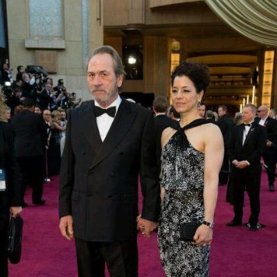 Tommy Lee Jones is on a tuxedo while Dawn Laurel-Jones is wearing a grey dress with unique patterns on it.